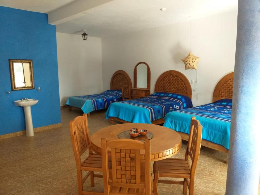 una camera con tre letti e un tavolo con sedie di Hotel Villas Monteli Suites Cuernavaca a Cuernavaca