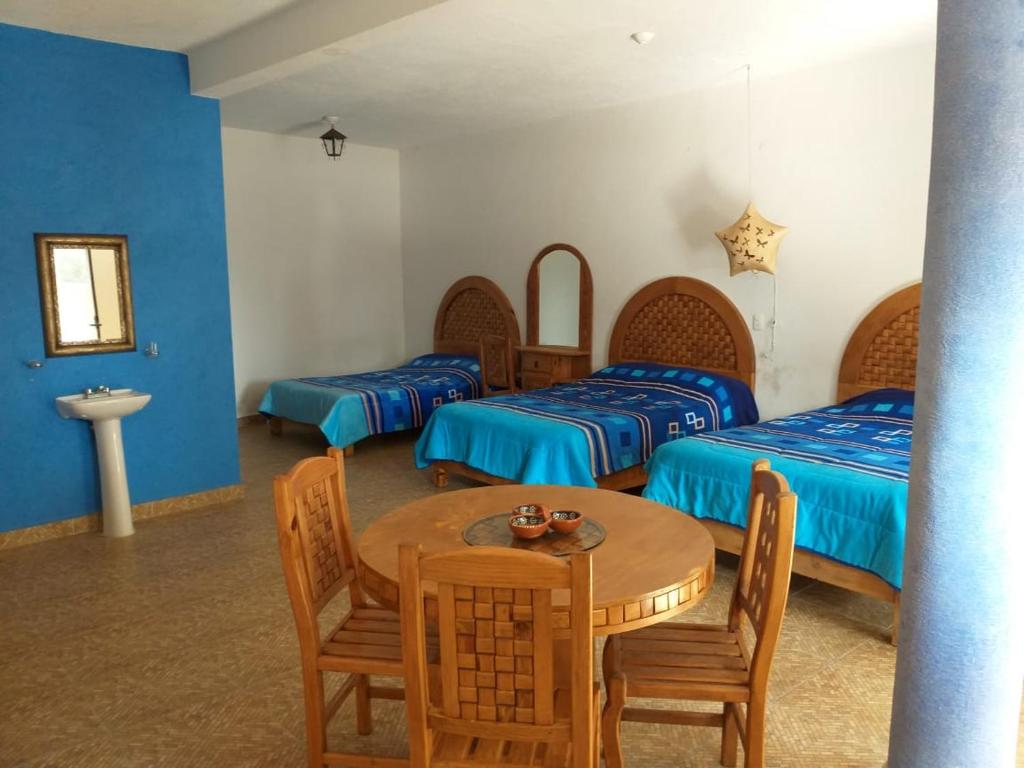 a room with three beds and a table and chairs at Hotel Villas Monteli Suites Cuernavaca in Cuernavaca