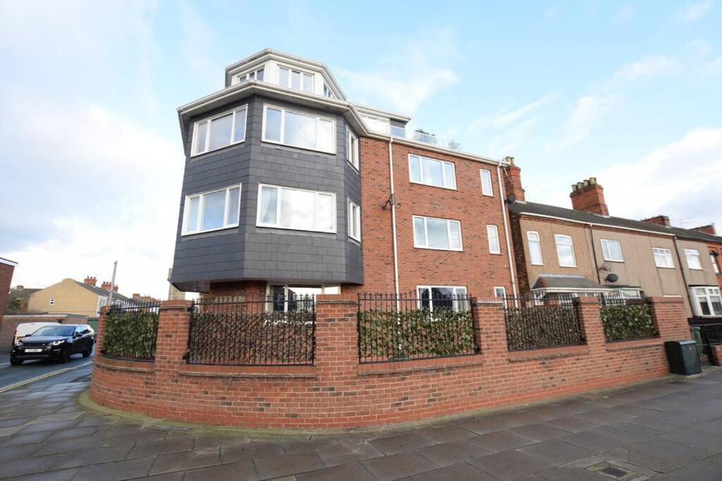 a house on a brick wall next to a street at Spacious 2 bedroom apartment Cleethorpes in Cleethorpes