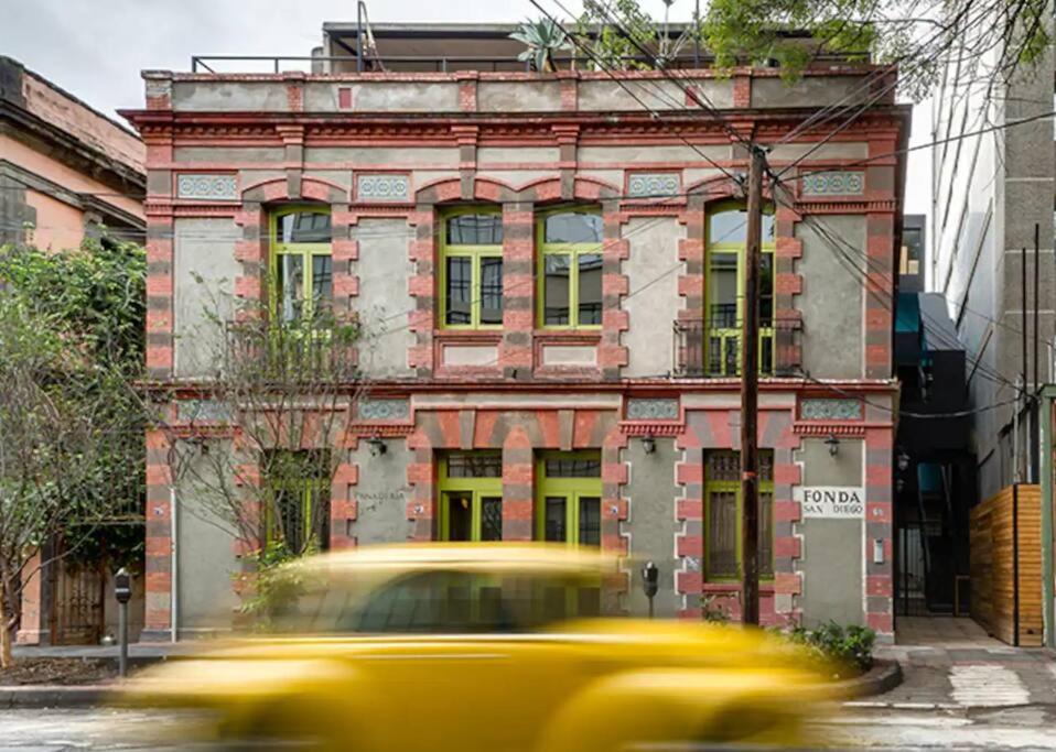 un taxi amarillo pasando por un edificio viejo en Hip Loft in Historic Building, en Ciudad de México