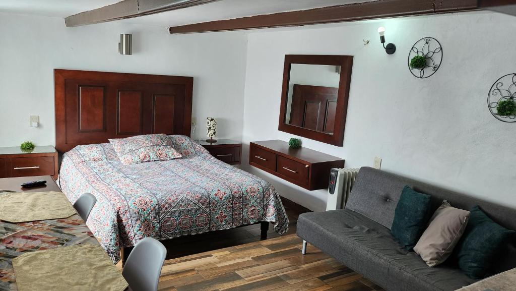 a bedroom with a bed and a couch and a mirror at Depa #6 Tipo Loft en Planta Alta en Centro Histórico in Zacatecas
