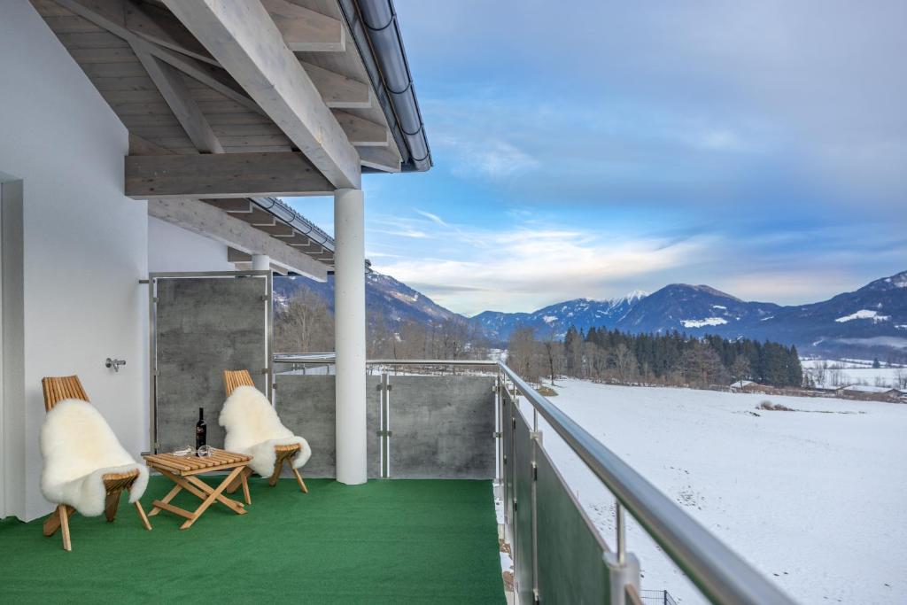 un balcón con 2 sillas, una mesa y una montaña nevada en Berg Apartment-Berg im Drautal en Berg im Drautal