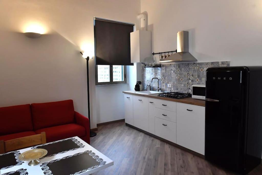 a kitchen with a black refrigerator and a red couch at Il Garibaldino in Livorno