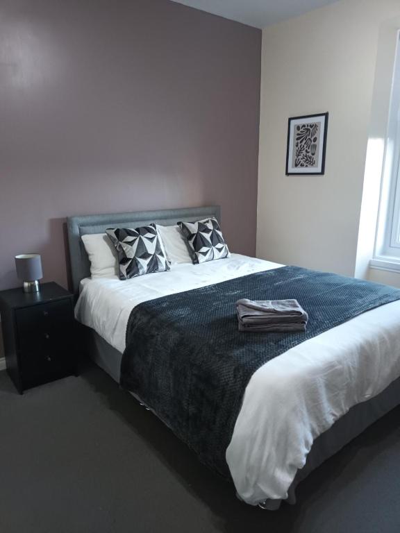 a bedroom with a large bed with a black blanket at The Beath Inn in Cowdenbeath