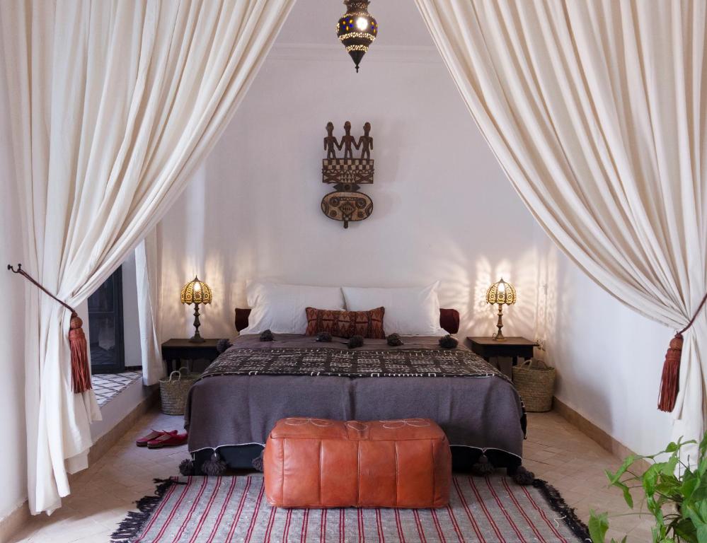 a bedroom with a bed with curtains and a rug at Riad Al Wifak in Marrakesh