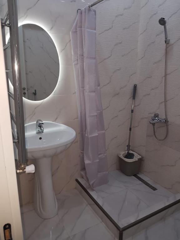 ein Bad mit einem Waschbecken und einer Dusche mit einem Spiegel in der Unterkunft Квартира в аренду in Tbilisi City