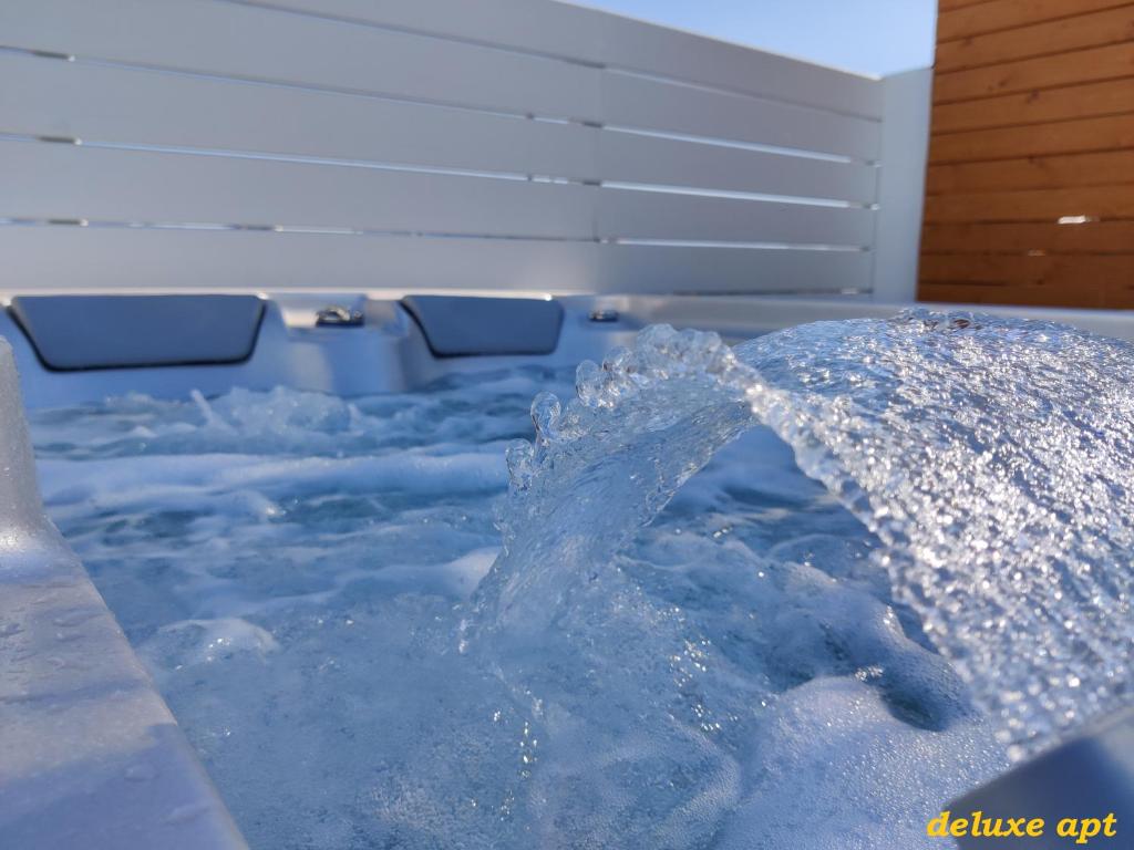 a hot tub with blue water and an umbrella at Aphrodite Luxury Apartments in Agios Prokopios