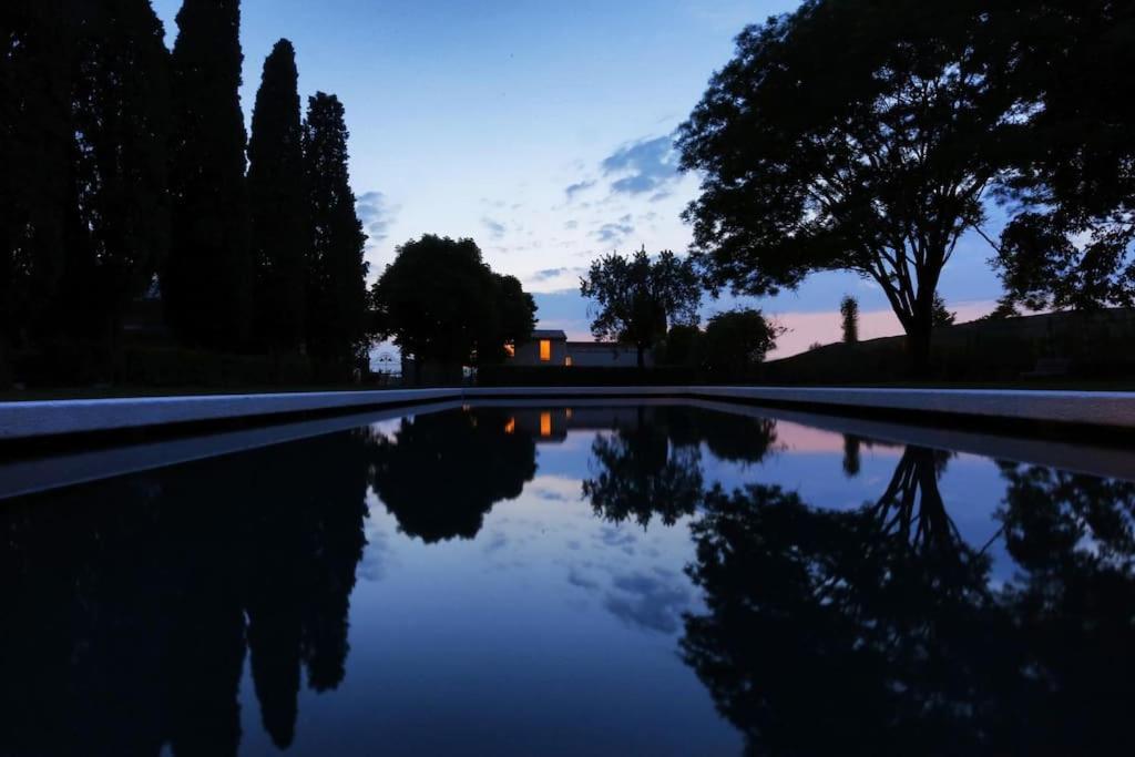 uma piscina de água com árvores e um edifício ao fundo em Brick house em Sommacampagna