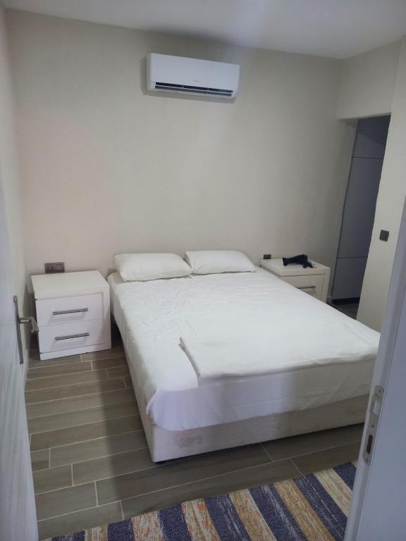 a bedroom with a white bed and a night stand at Yaz kış güzel manzaralı ev in Bodrum City