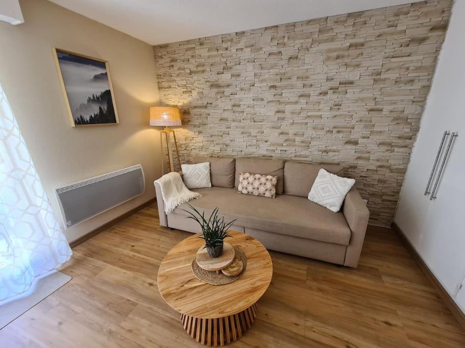un soggiorno con divano e tavolo di Appartement au calme dans residence avec piscine a Boersch