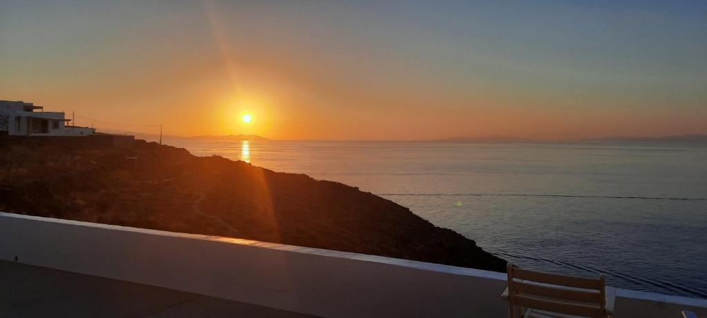 a sunset over the ocean with a wooden bench at Sifnos "Sofia apartments" sea view in Faros