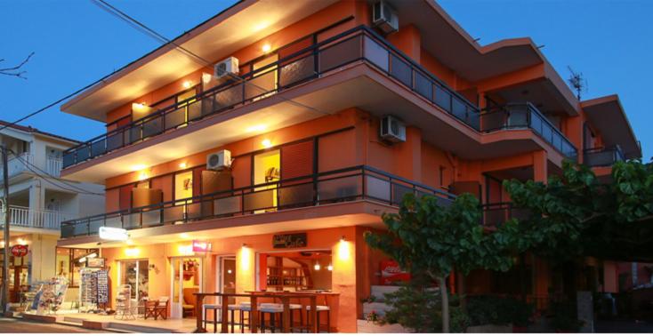 een groot oranje gebouw met een balkon bij Astir Rooms in Póros