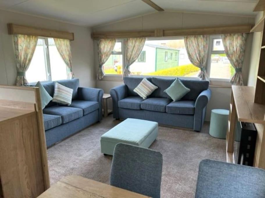 ein Wohnzimmer mit blauen Sofas und einem Tisch in der Unterkunft Leylandii 2 Bed Holiday Home in picturesque town. in Knaresborough