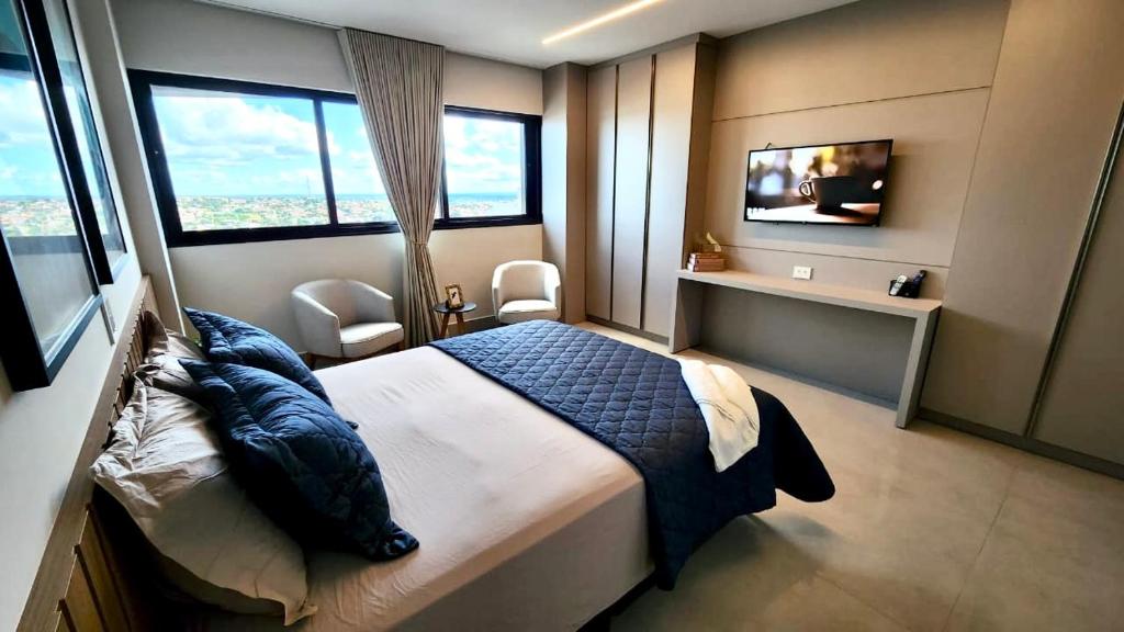 a bedroom with a bed and a tv and windows at Flat de Luxo c/ Quarto Privativo 21º Andar Vertigo in Campo Grande