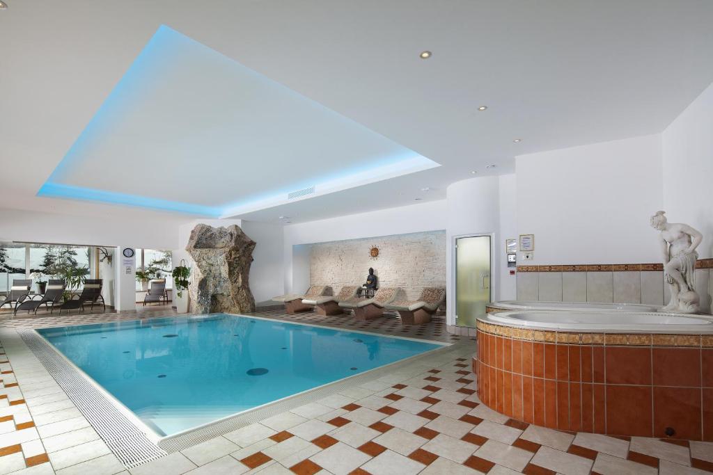 a large swimming pool in a building with a tub at Alpenhotel Weiherbach Berchtesgaden Hallenbad und Sauna in Berchtesgaden