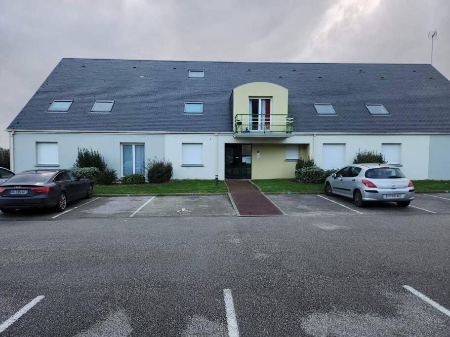 a building with two cars parked in a parking lot at Au feu de Berque in Cherbourg en Cotentin