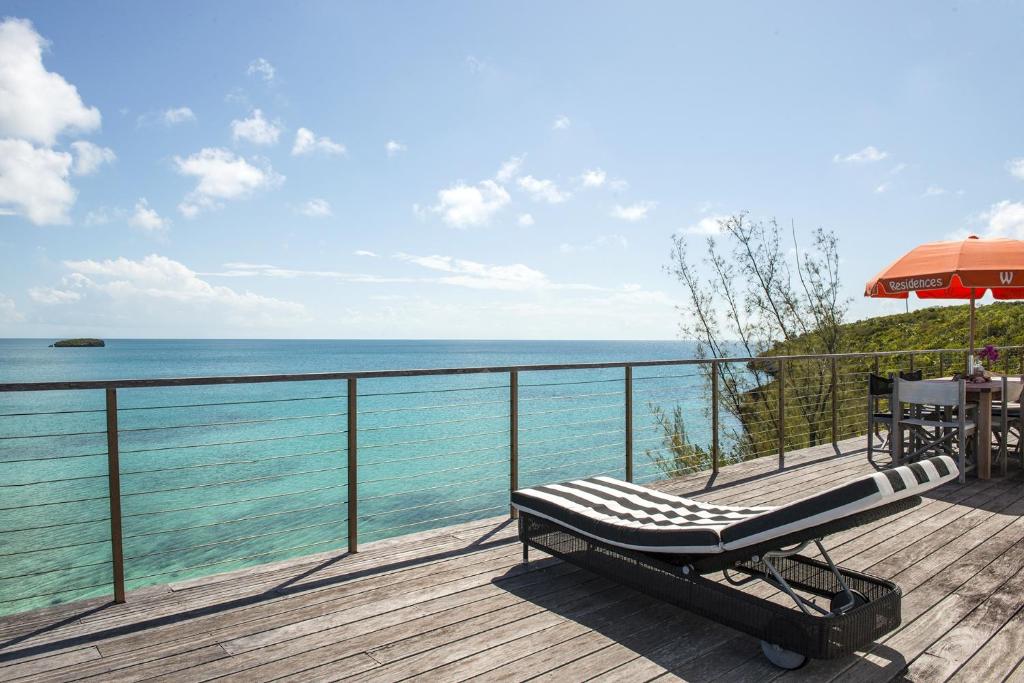 a bench on a deck with a view of the ocean at Touch of Class home in Savannah Sound