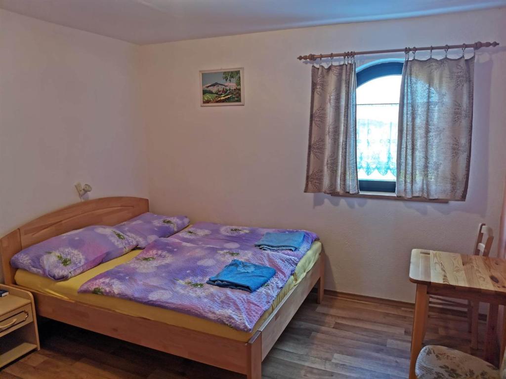 Un dormitorio con una cama con sábanas moradas y una ventana en Penzion a vinný sklípek Mušov, en Pasohlávky