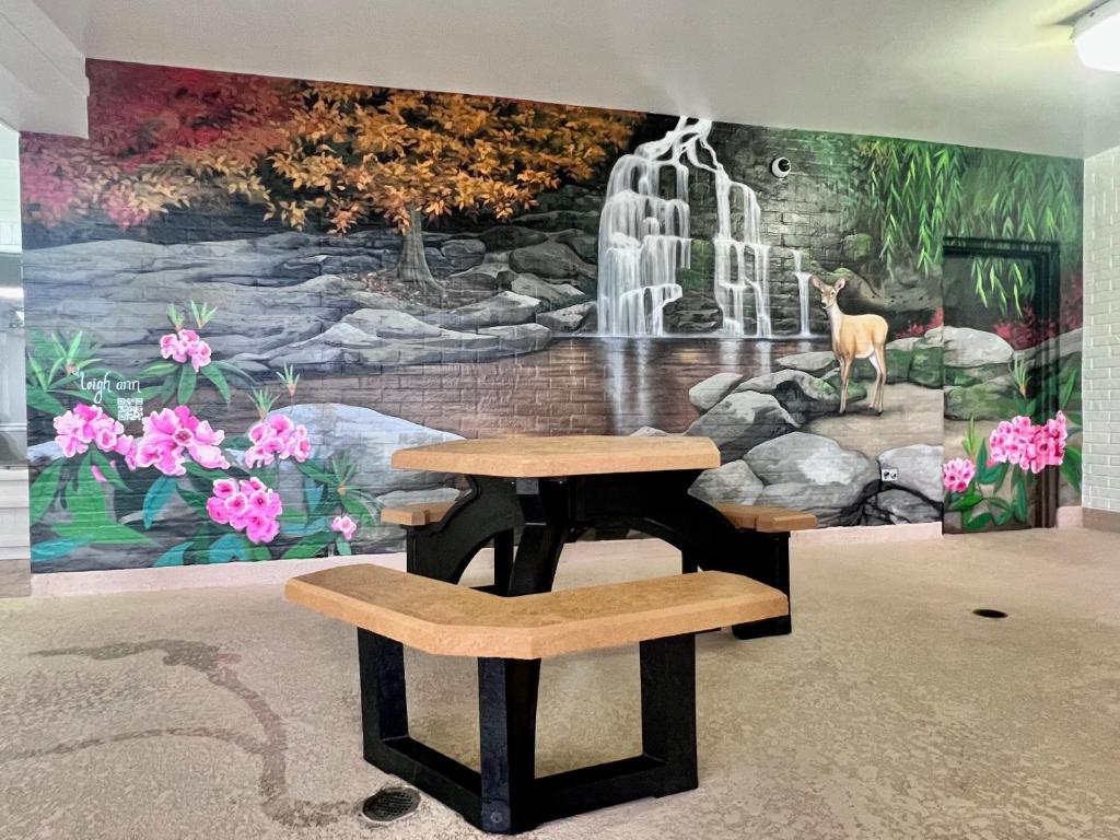 a table and two benches in front of a mural at Clarion Inn Willow River in Sevierville