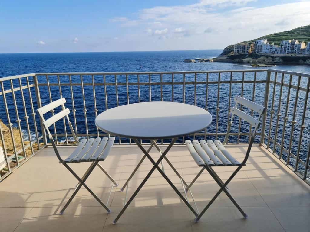un tavolo e due sedie su un balcone con vista sull'oceano di Sea Breeze a Żebbuġ