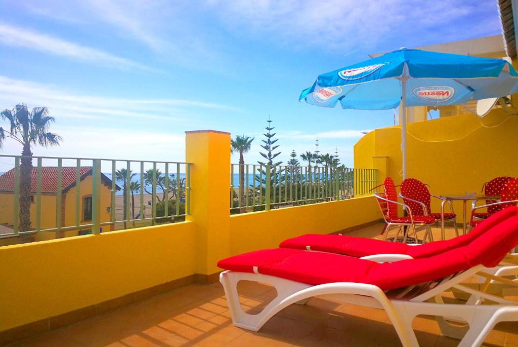 einen Balkon mit einem Tisch, einem Sonnenschirm und Stühlen in der Unterkunft HOSTAL LA ESTACION in Benajarafe