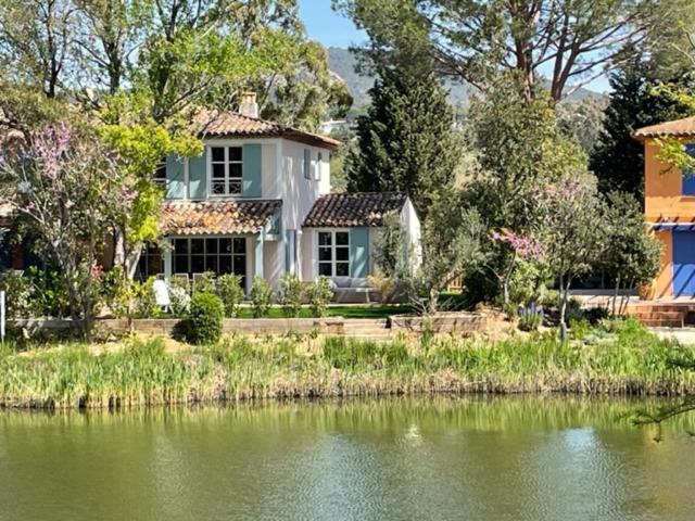 a house next to a body of water at Les Restanques Maison du lac 4 chambres in Grimaud