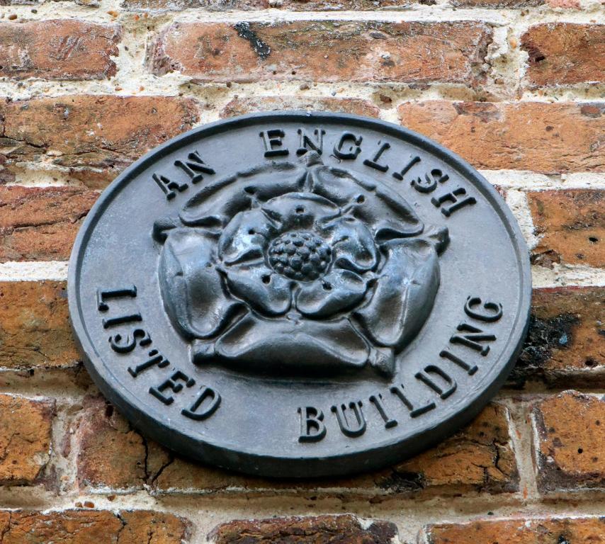 une plaque métallique sur un mur de briques avec une fleur dans l'établissement Trinity Square, Margate, à Kent
