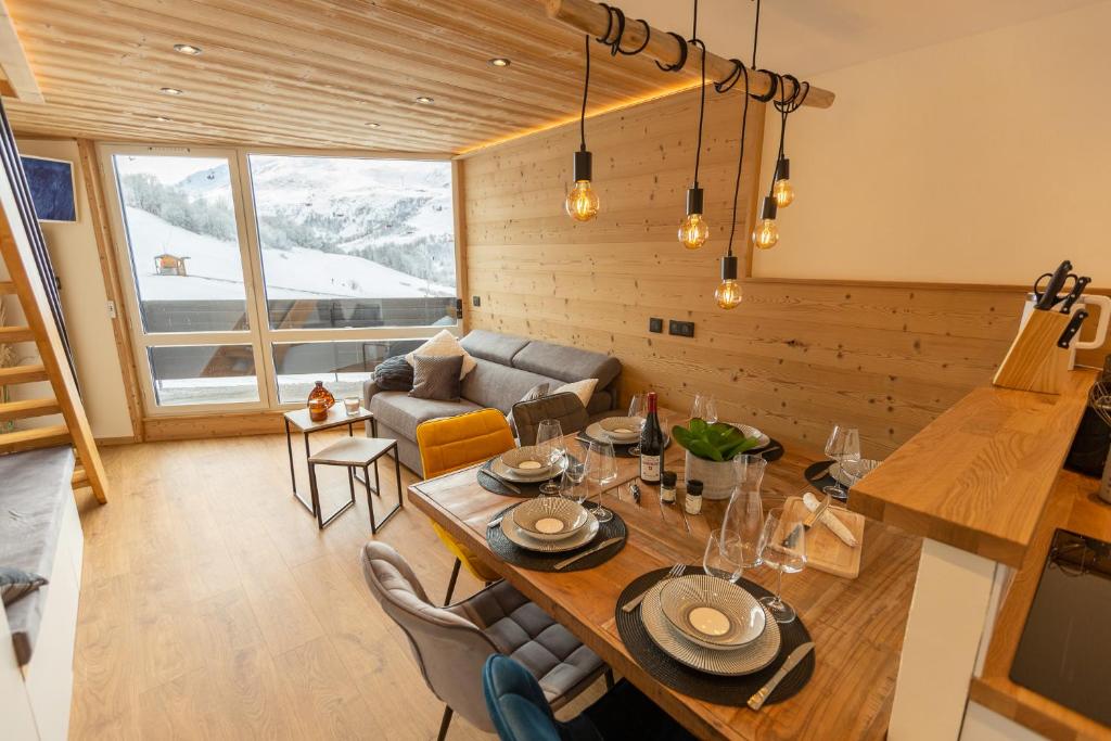 een woonkamer met een tafel en een bank bij Duplex cosy au pied des pistes vue montagne in Les Menuires