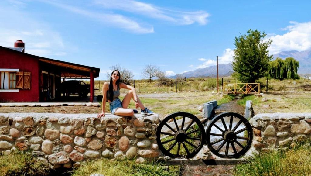 a woman sitting on a wall next to a cannon at Ruedas Negras Casa de Campo in Los Árboles