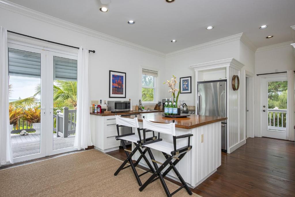 a kitchen with white cabinets and a table and chairs at Sand Dollar Cottage cottage in Rock Sound