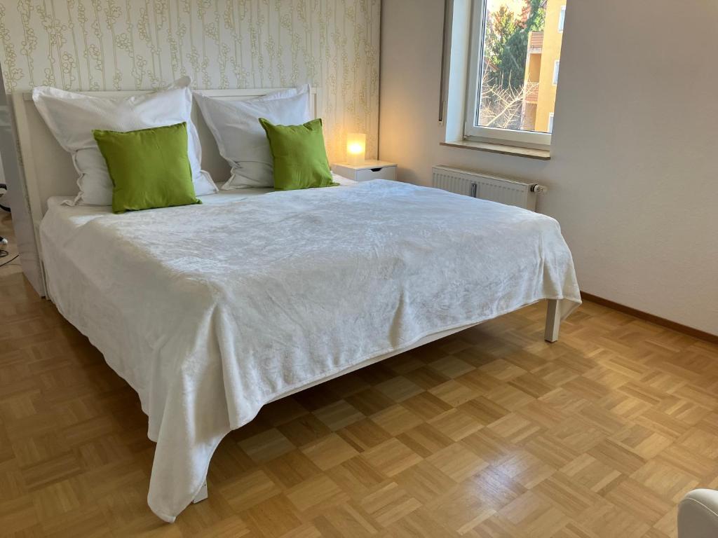 1 cama blanca grande con almohadas verdes en una habitación en Ferienwohnung-Ludwigsburg-City, en Ludwigsburg