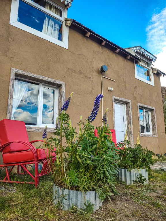 a house with two chairs and flowers in front of it at Los Lupinos in El Chalten