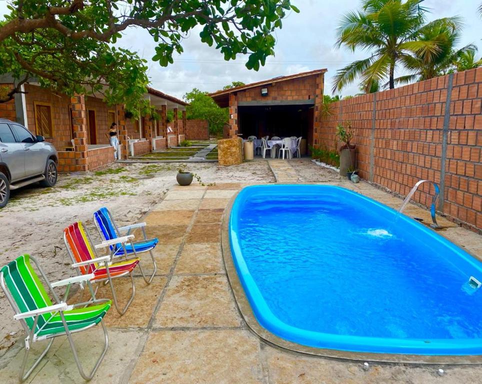 a swimming pool with chairs and a table at Pousada vida nos lençóis in Barreirinhas