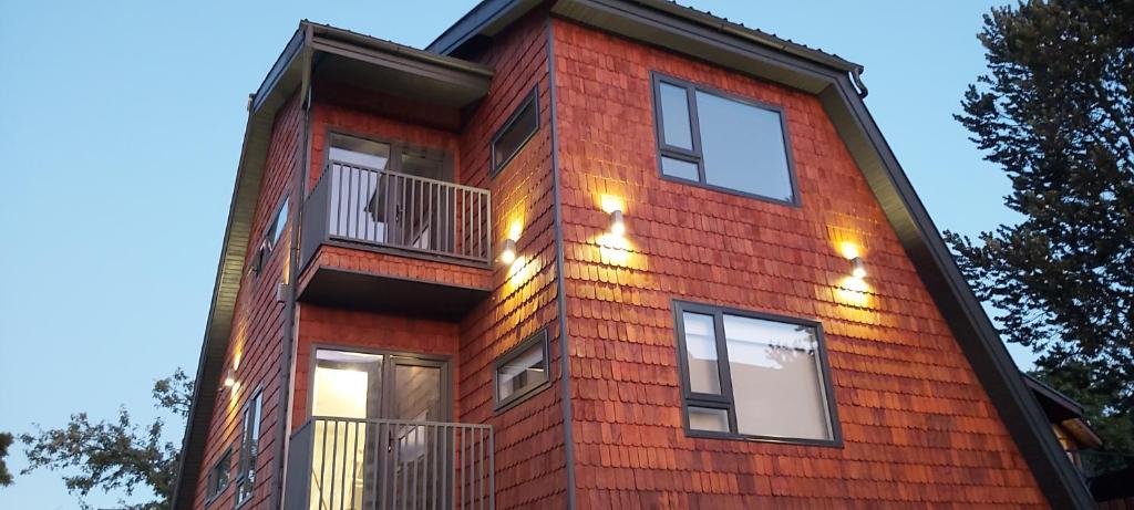 ein rotes Backsteingebäude mit Fenstern und einem Balkon in der Unterkunft Patagonia Route Apartments in Puerto Varas