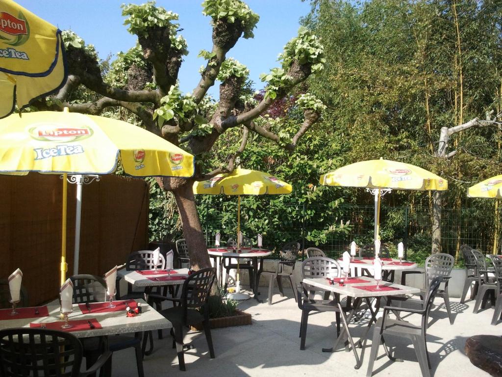 a group of tables and chairs with umbrellas at Hotel Alain et Martine in Viviers-du-Lac