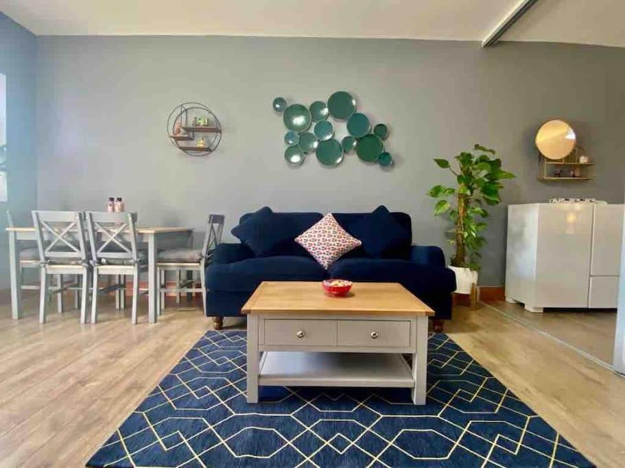 een woonkamer met een blauwe bank en een tafel bij Lovely 1 bed Studio Apartment with free parking in Oxford