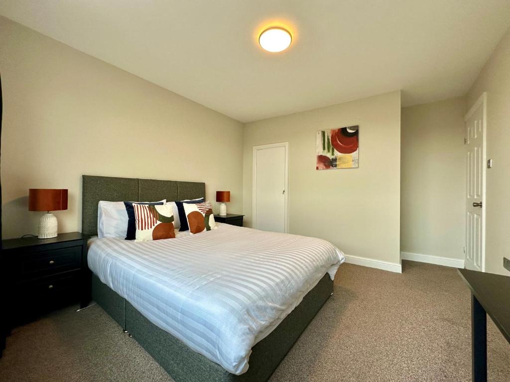um quarto com uma cama grande e lençóis brancos em Spacious 3 double bedroomed house in Bicester em Bicester