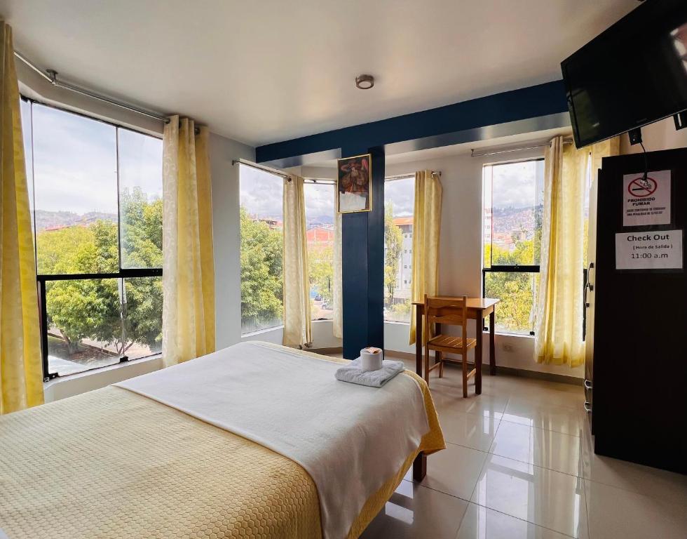 1 dormitorio con 1 cama grande, ventanas y escritorio en Ejecutivo Palace Sumak, en Cusco