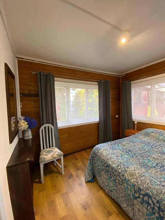 1 dormitorio con 1 cama, 1 silla y ventanas en La Guapa Hostel, en Puerto Varas