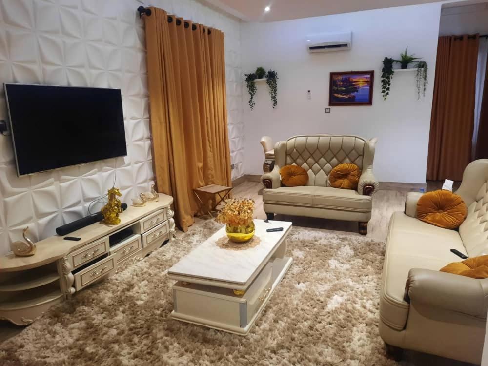 un soggiorno con TV a schermo piatto a parete di Akura Villa Adeniyi Jones Ikeja a Ikeja