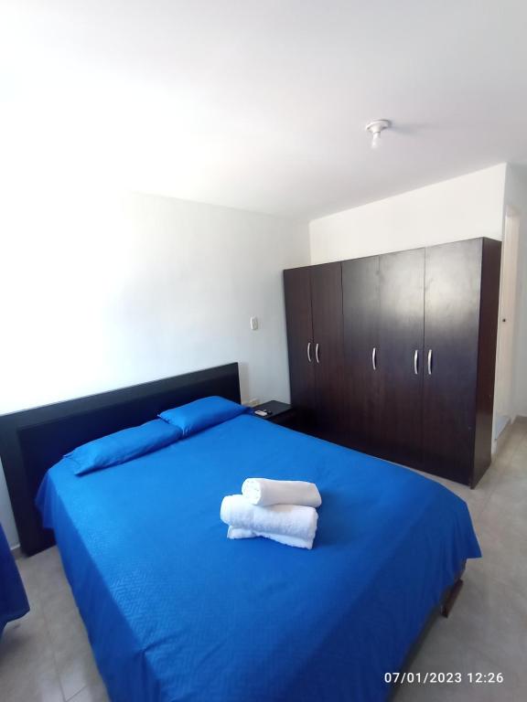 a bedroom with a blue bed with two towels on it at Habitación doble cómoda in Valledupar