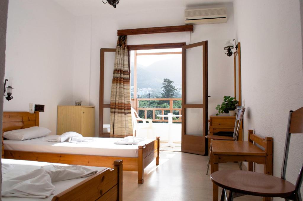 a room with two beds and a table and a window at Hotel Velissarios in Hersonissos