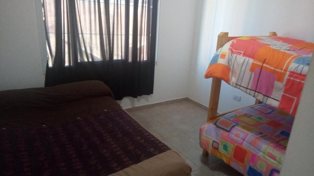 1 dormitorio con cama, ventana y silla en Alojamientos Malargüe en Malargüe
