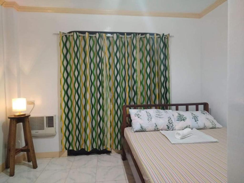 - une chambre avec un lit et un rideau vert dans l'établissement Deja Homestay Siargao, à Del Carmen