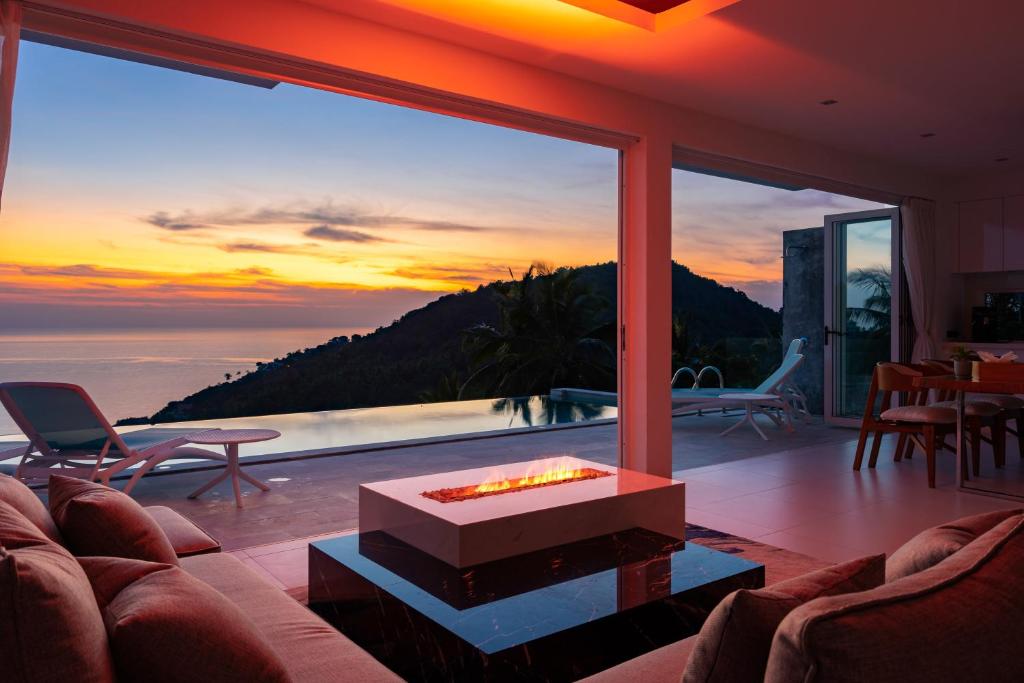 een woonkamer met een open haard en uitzicht op de oceaan bij Villa Melo in Chaweng Noi Beach