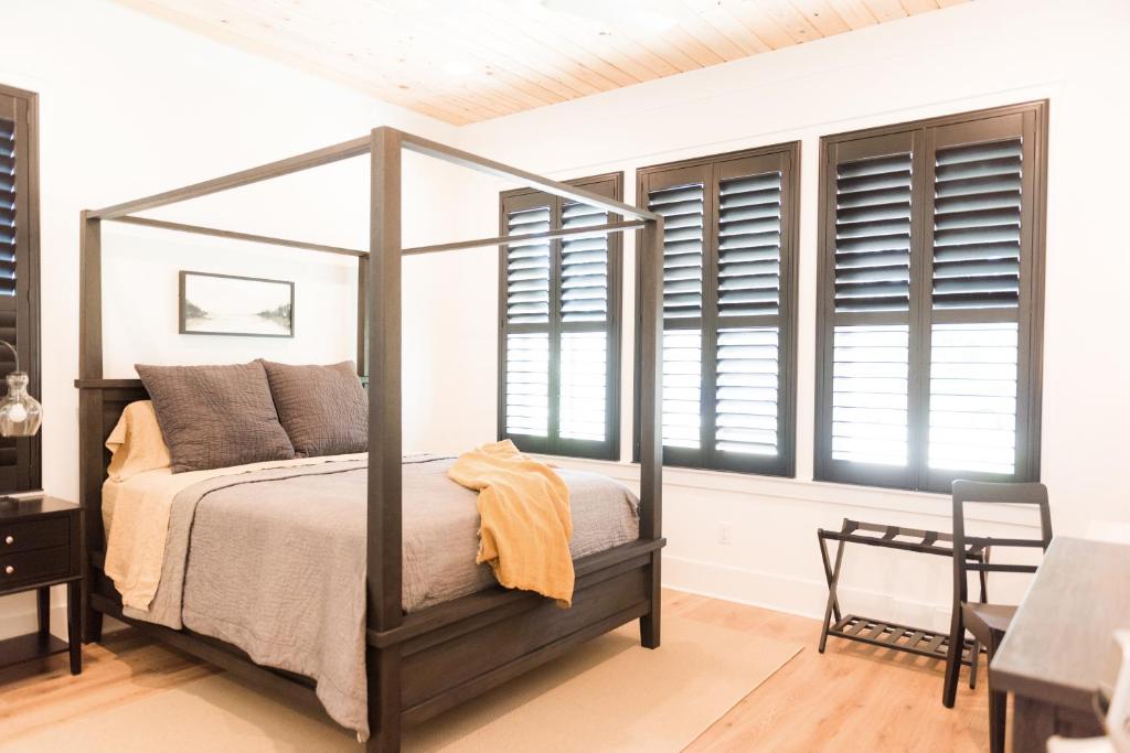 a bedroom with a canopy bed and windows at Haven House in Pensacola