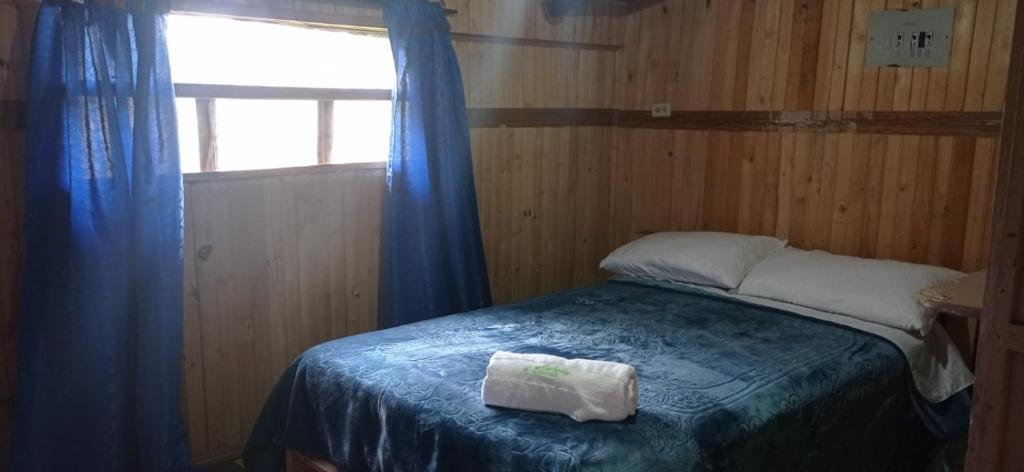 a bedroom with a bed with a blue blanket and a window at CABAÑA ENCANTO in Saboyá