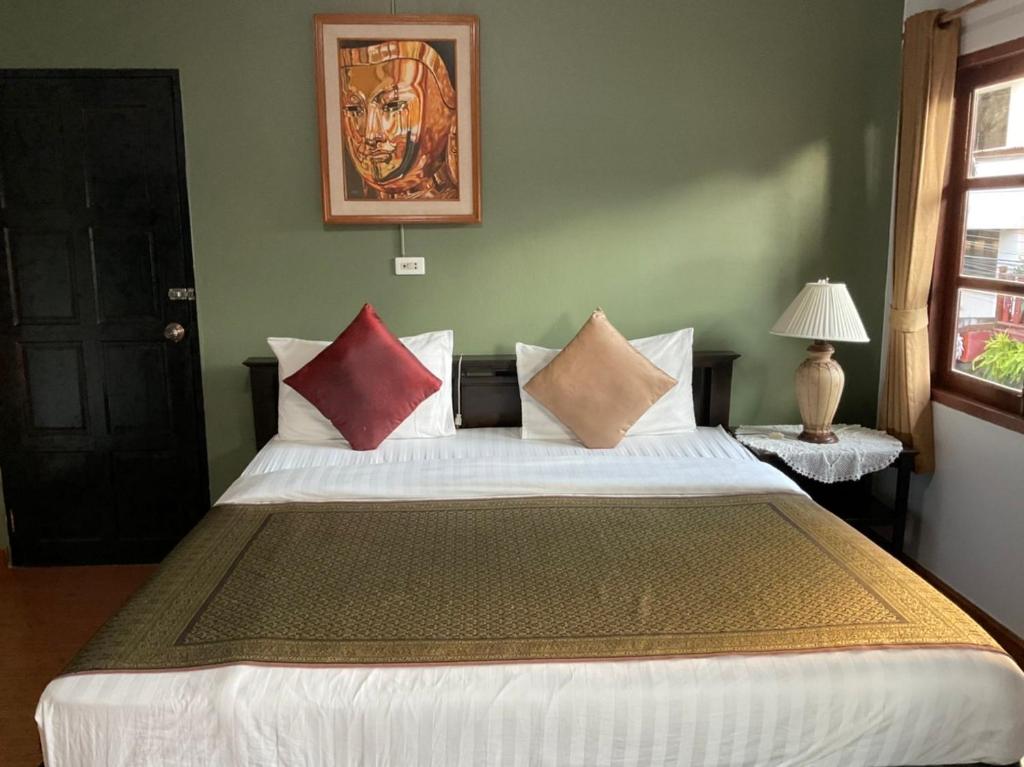 a bedroom with a large bed with pillows on it at Baan Klang Vieng in Chiang Mai