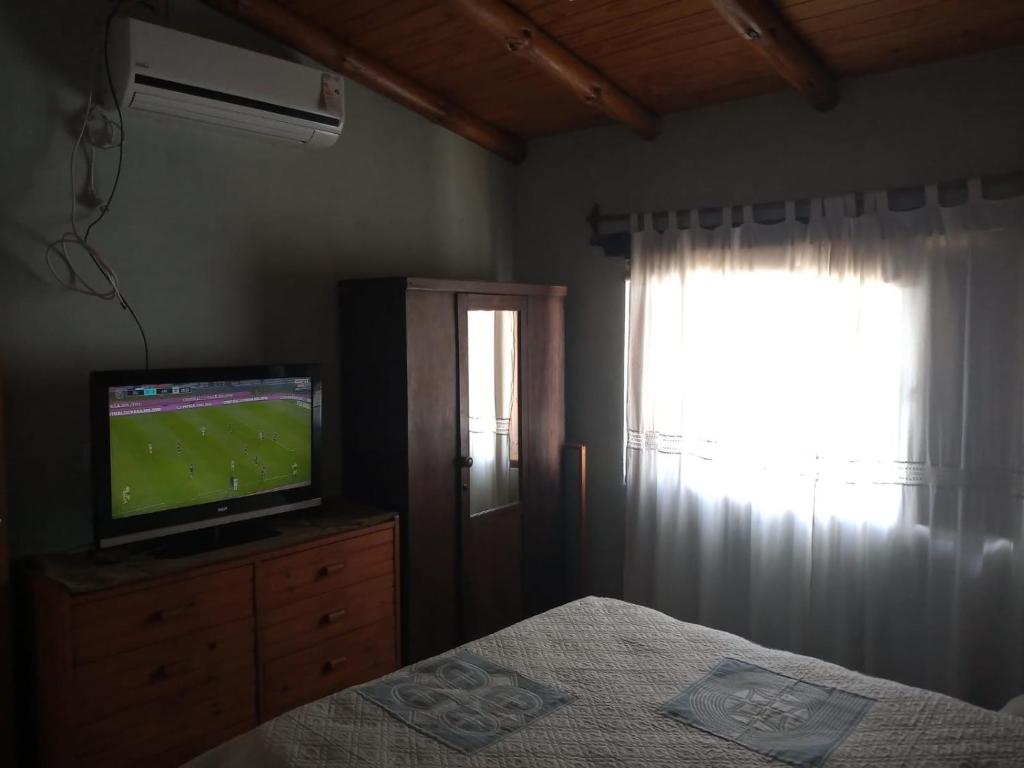 1 dormitorio con TV, 1 cama y ventana en Terrazas del Río en Achiras