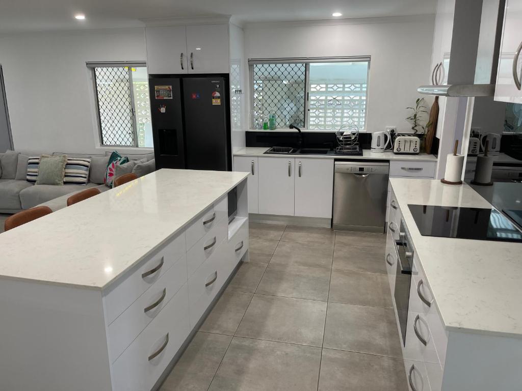 eine Küche mit weißen Schränken und einem schwarzen Kühlschrank in der Unterkunft Cairns / Edge Hill Stylish Villa A in Edge Hill